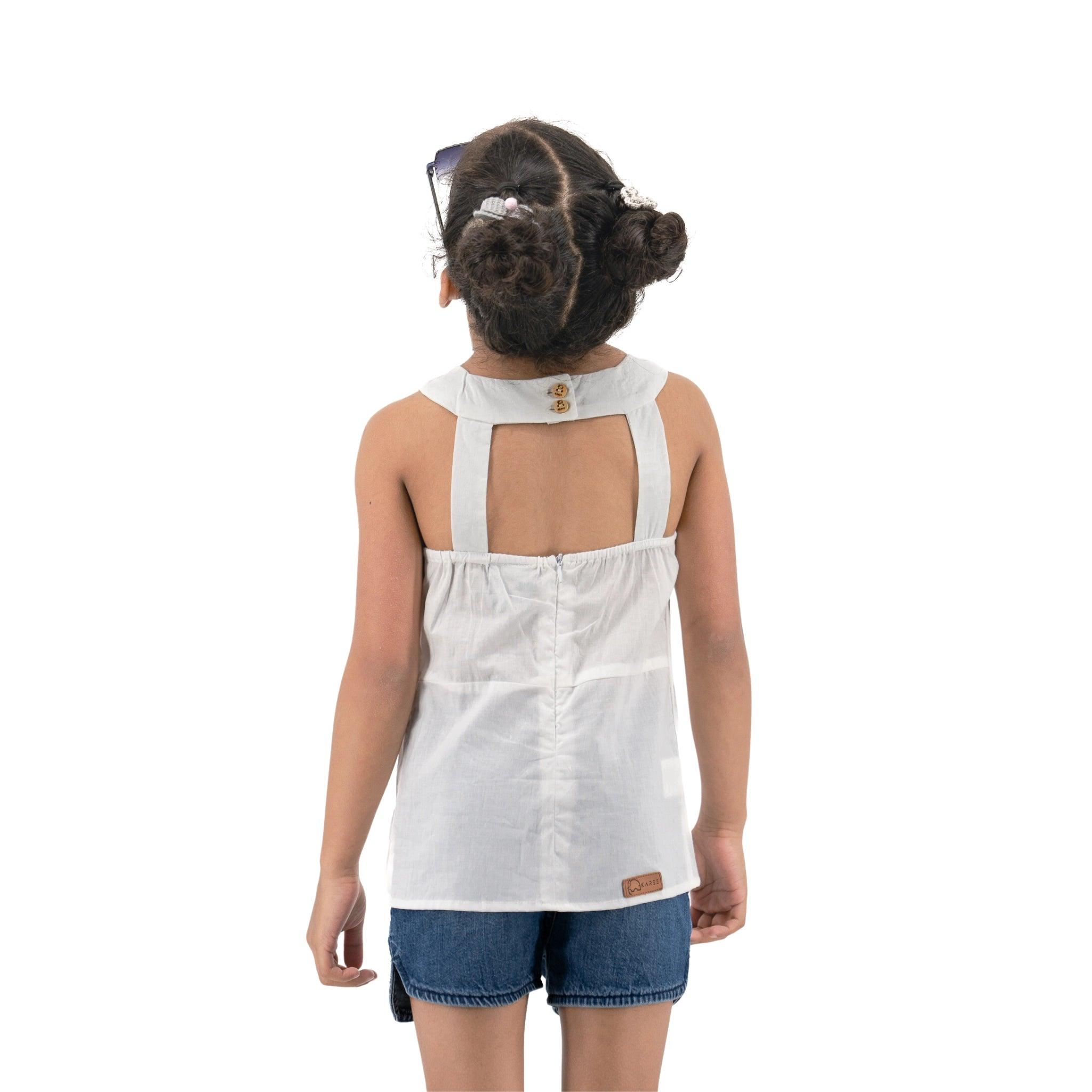 A young girl seen from behind, wearing a Karee Brilliant White Cotton Bib Neck Top for kids and denim shorts, standing against a white background.