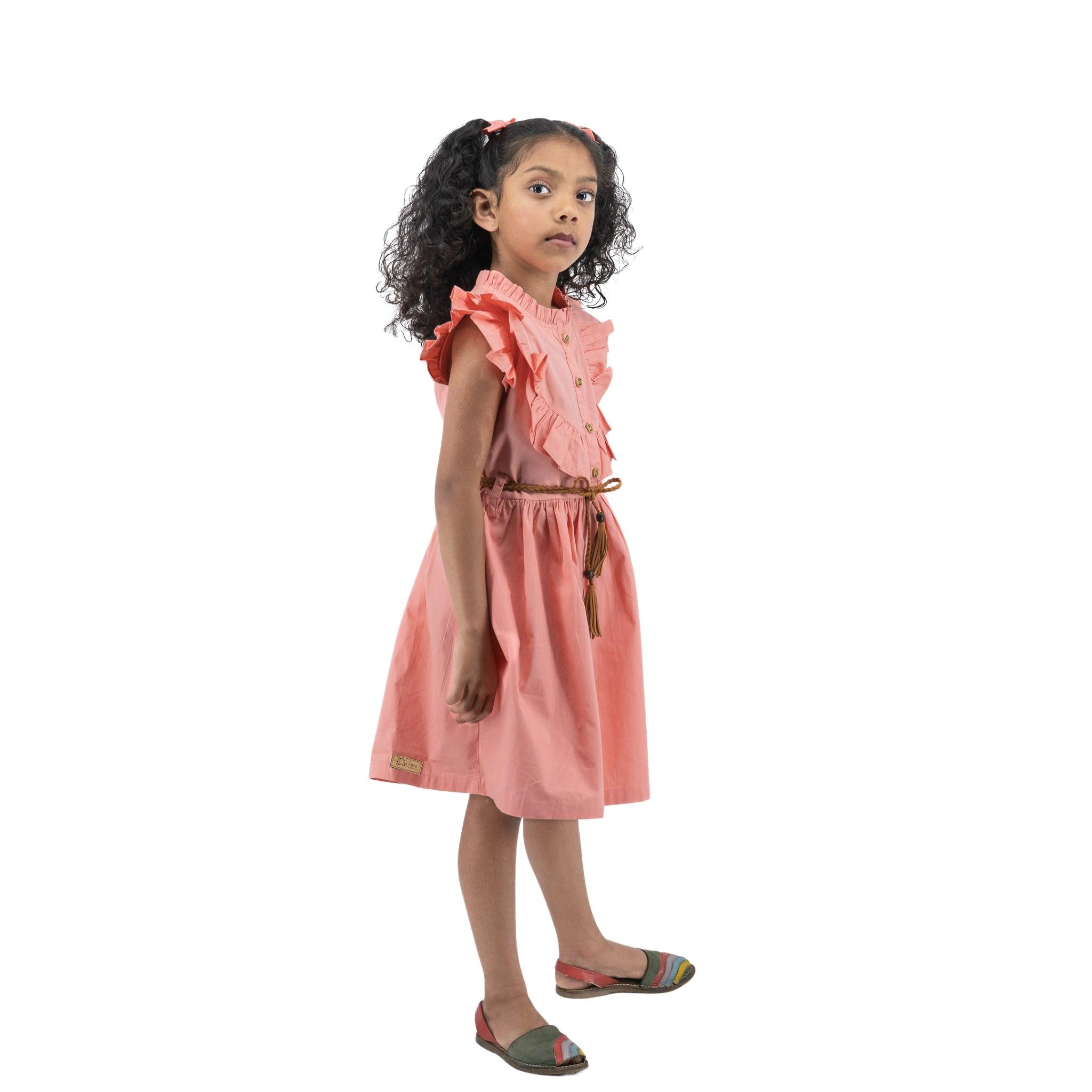 Young girl in a Karee Peach & Cream Butterfly Sleeve Cotton Dress looking surprised, standing against a white background.