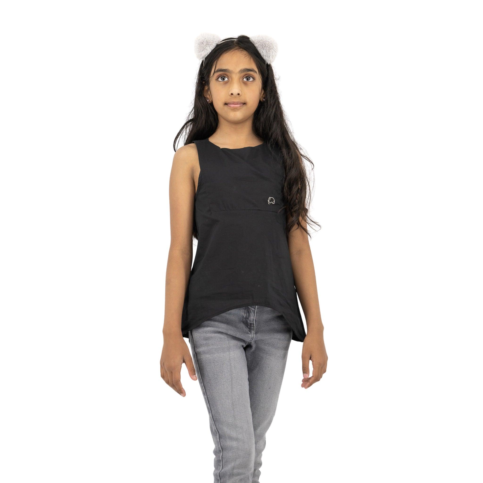 A young girl wearing the Karee Black Beauty Cotton Bib Neck Top for kids and grey jeans, standing against a white background, looking to the side.