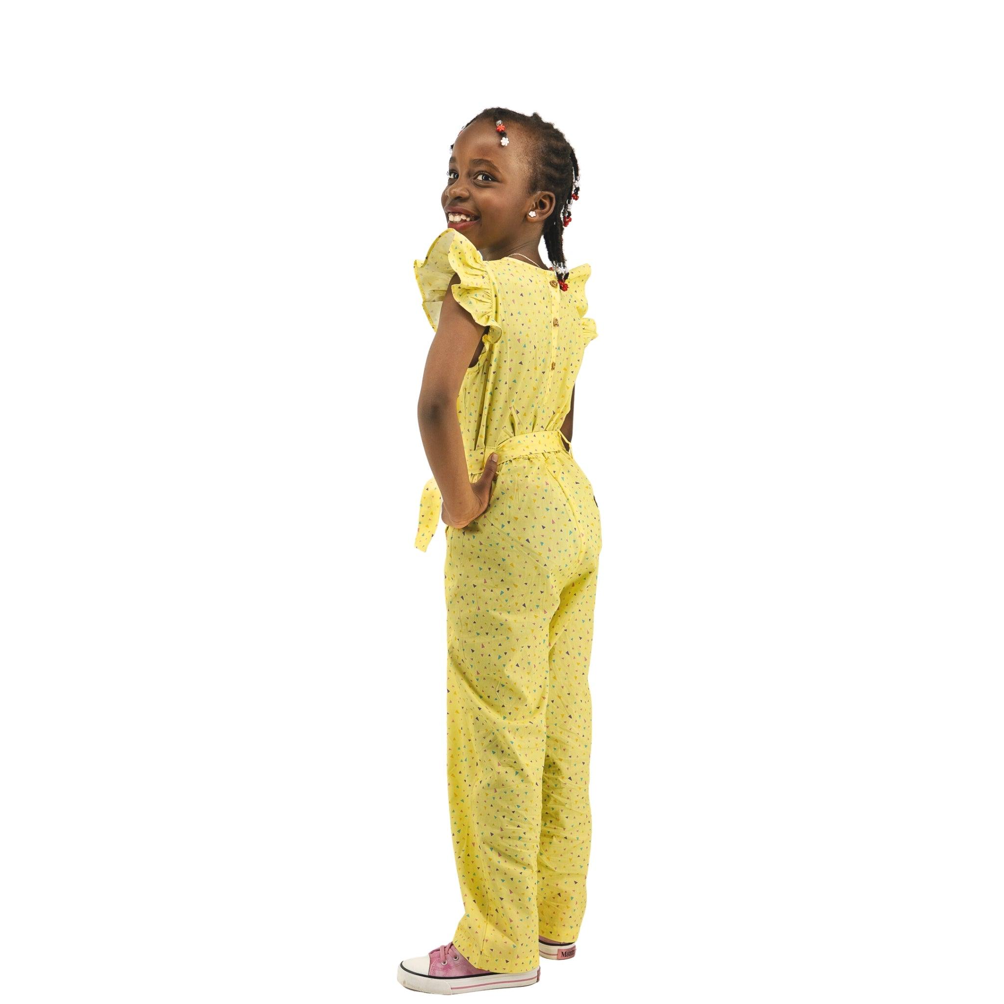 Young girl in a Karee Lemon Meringue Cotton V-Neck Jumpsuit for Girls with floral pattern, smiling and looking upwards, standing against a white background.