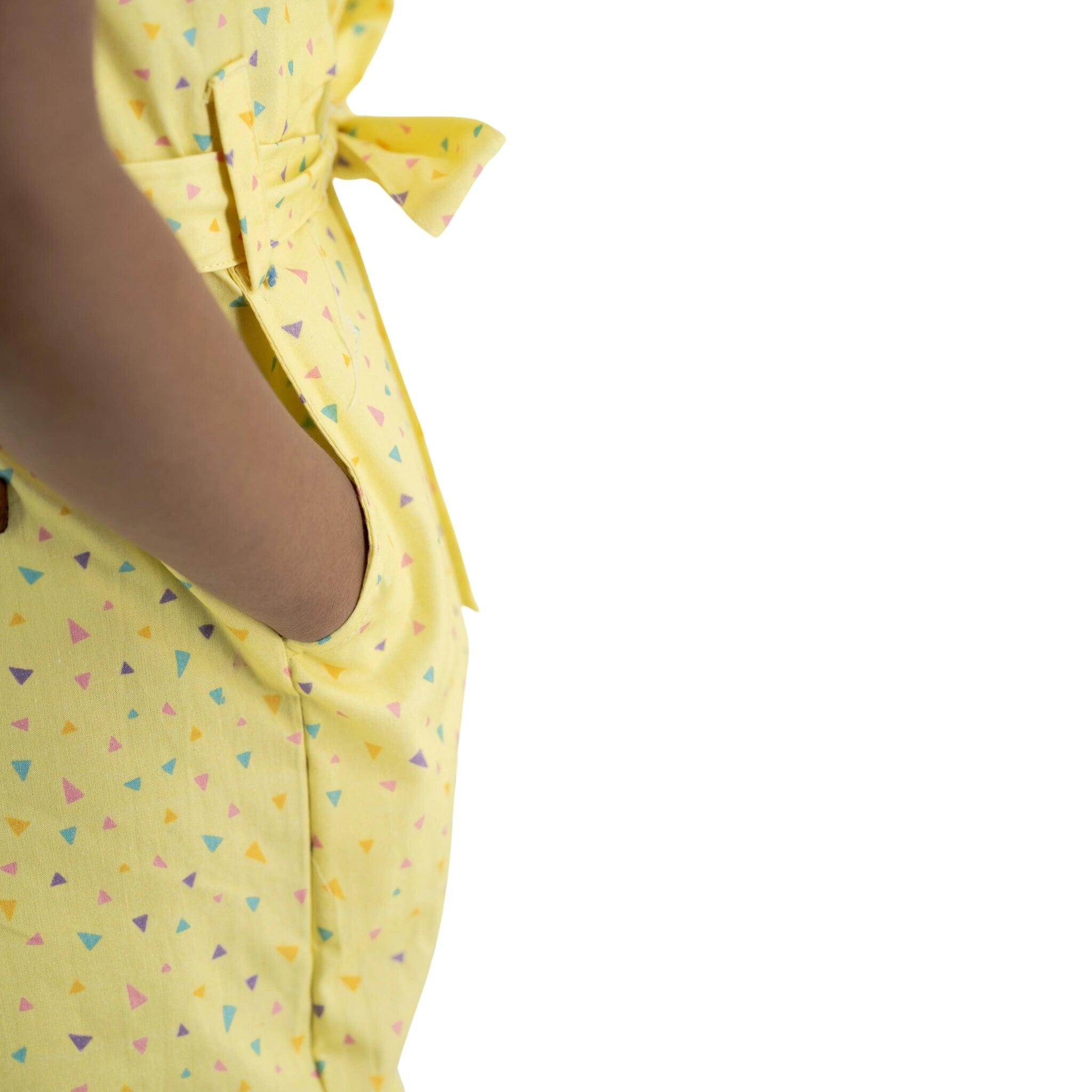 Close-up of a person wearing a Karee Lemon Meringue Cotton V-Neck Jumpsuit for Girls with a geometric triangle pattern, focusing on the side pocket.