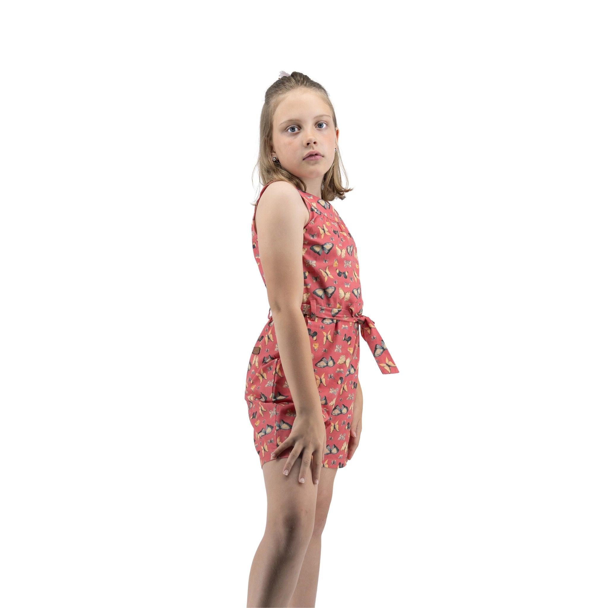 Young girl in a red floral Ruby Trek Cotton Romper by Karee looking over her shoulder against a white background.