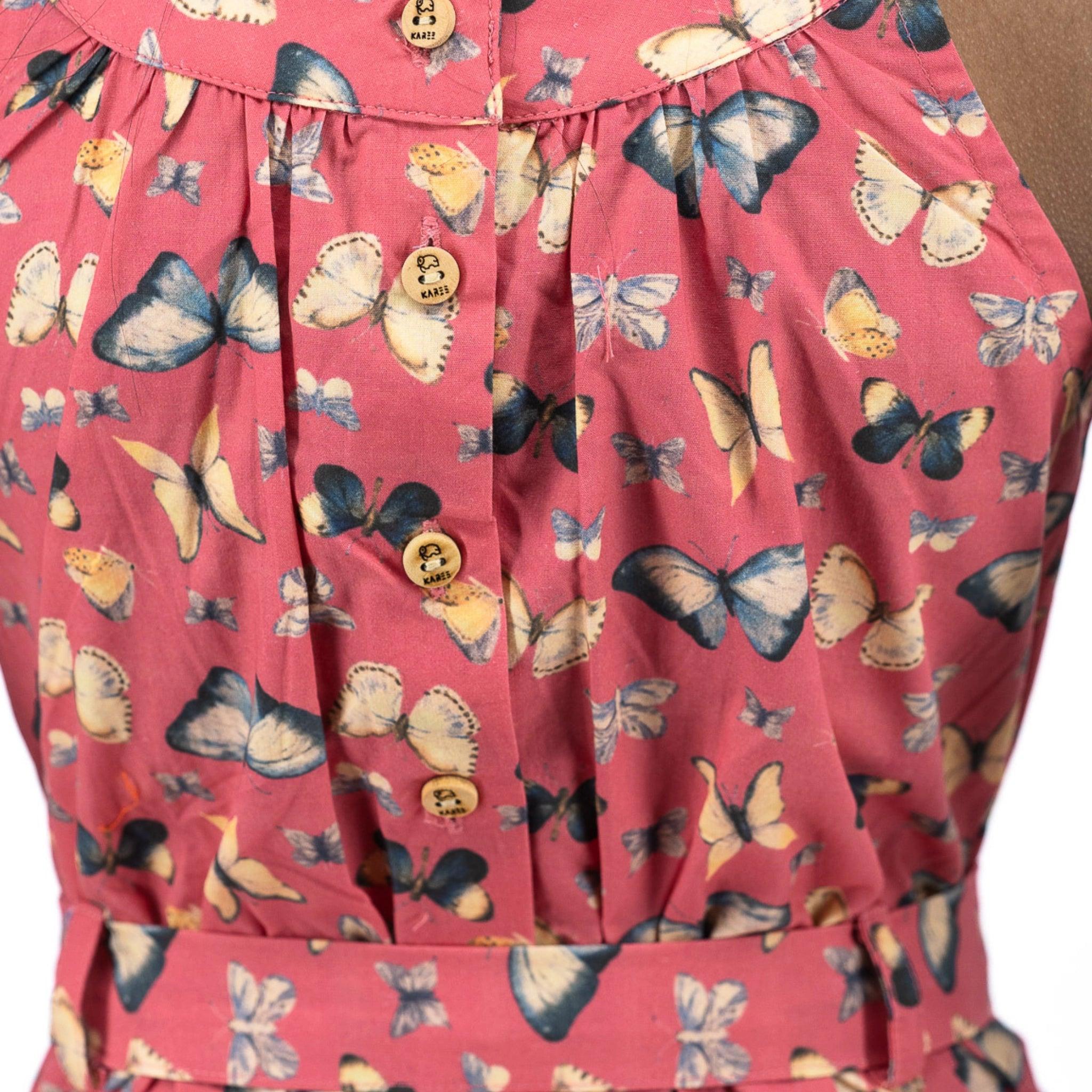 Close-up of a Karee Ruby Trek Cotton Romper with a pink and blue butterfly print and visible brown buttons.