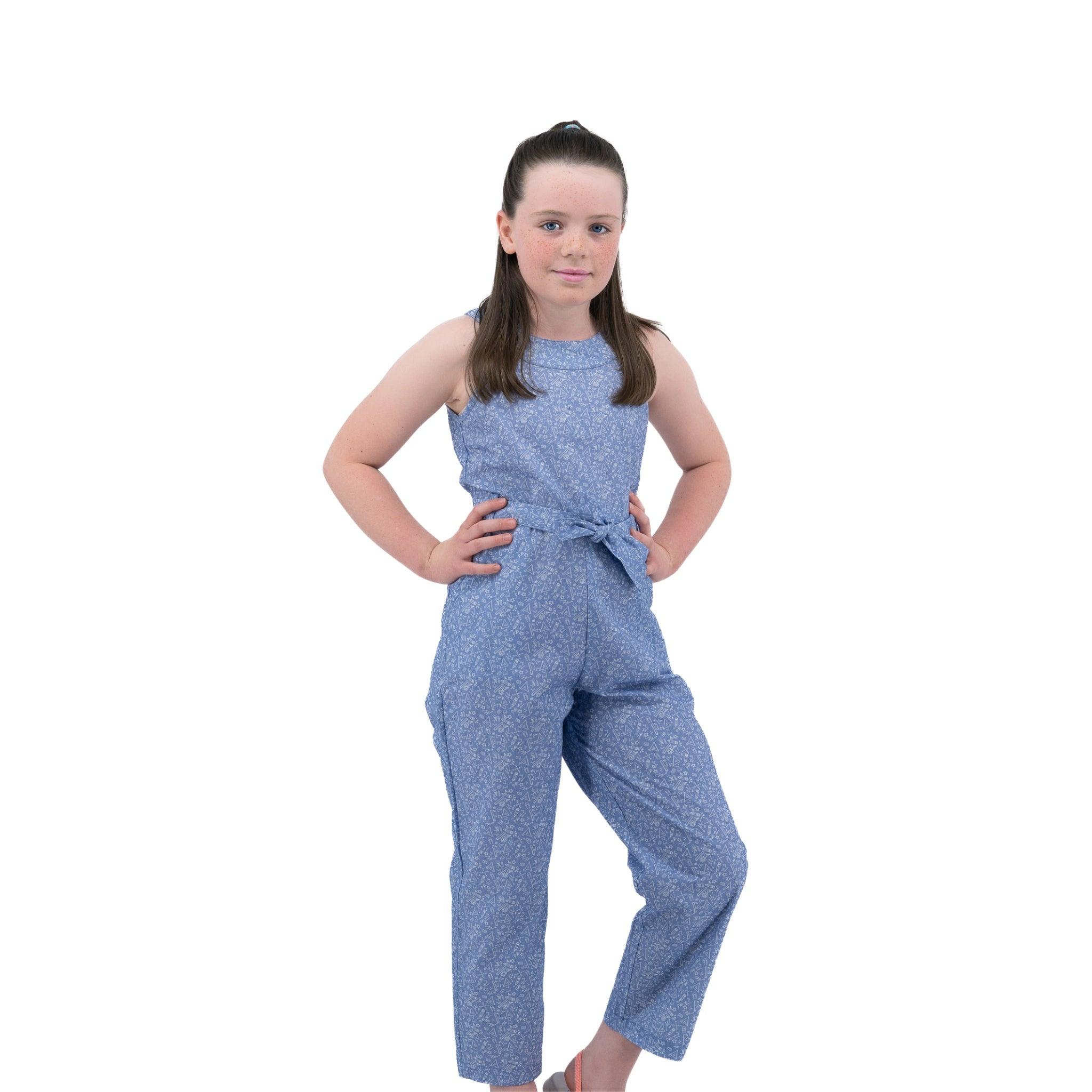 Young girl standing confidently with hands on hips, wearing a Karee Purple Impression Cotton Jumpsuit for kids, against a white background.